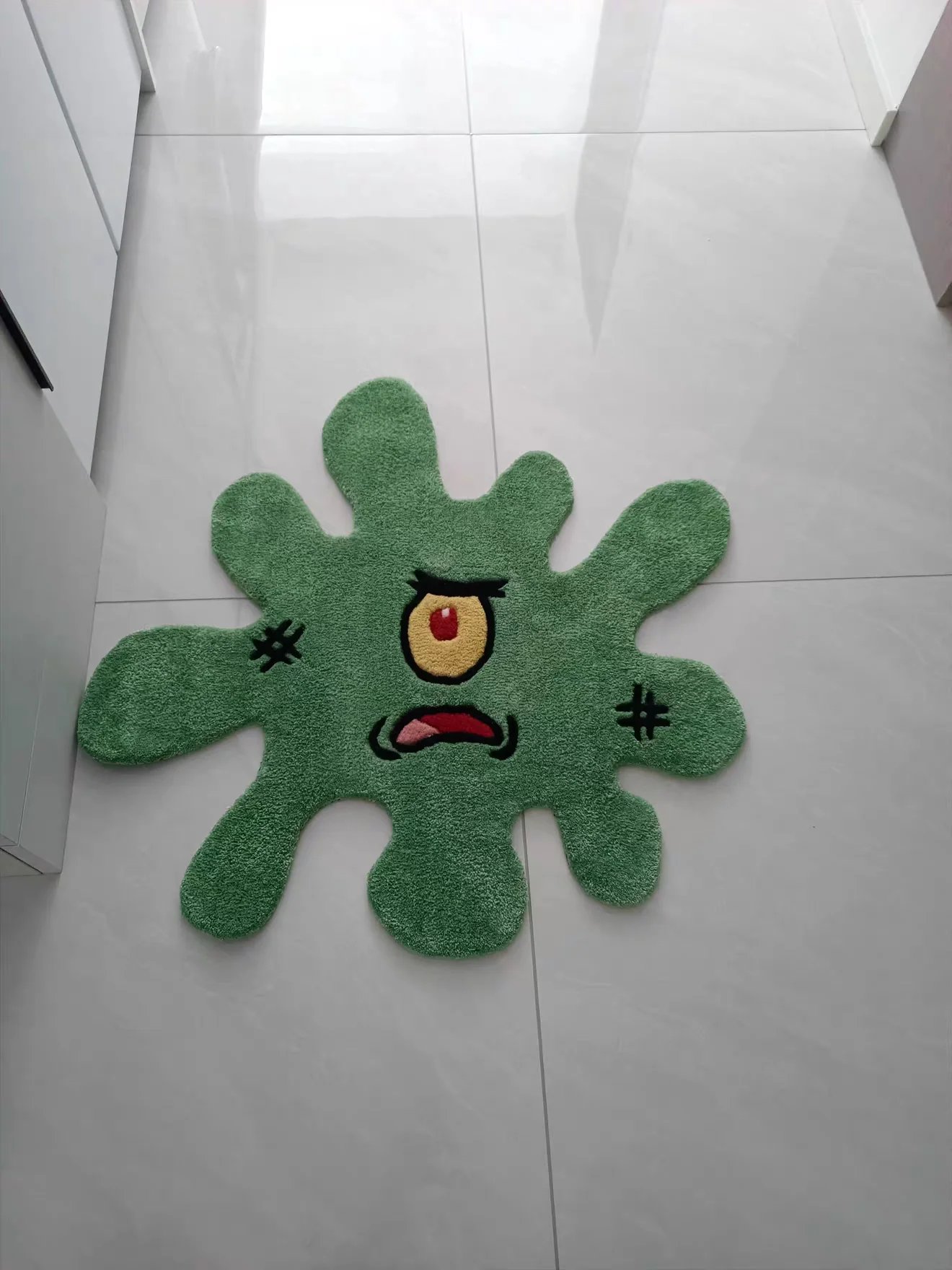 Green one-eye character rug on Chloe's tiled floor